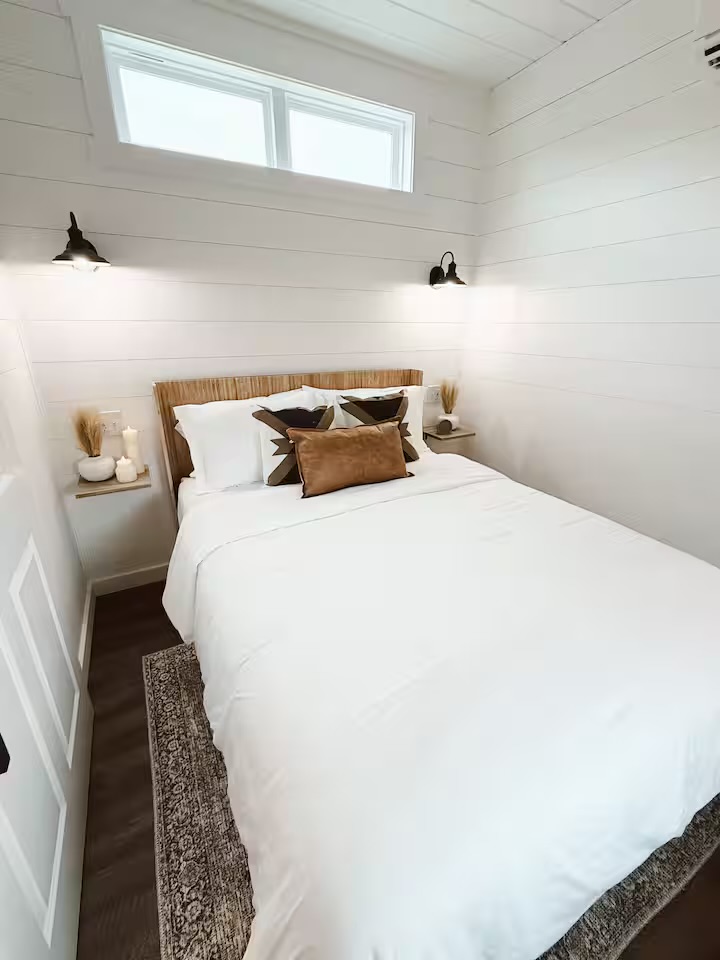 Tiny Timber bedroom with queen bed, wall sconces, and floating nightstands