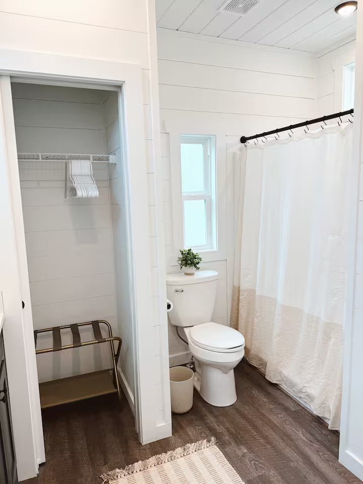 Tiny Timber bathroom with shower, closet, and shiplap walls