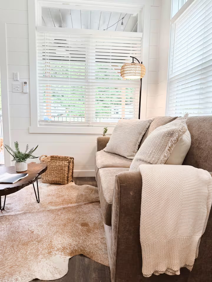 Tiny Timber living room with plush sofa, throw blanket, and cowhide rug
