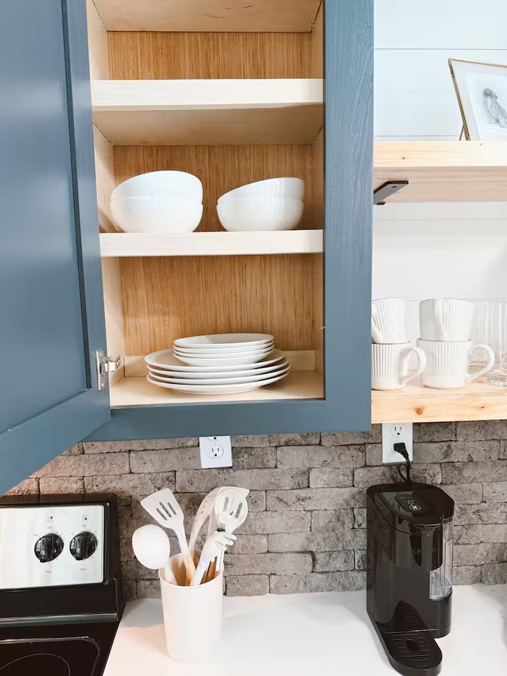 Tiny Timber open cabinet stocked with white dishes and bowls